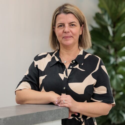 Professional headshot of Novela with plant in background